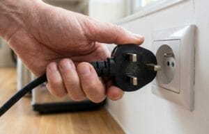 Man plugging in an appliance into a socket which has the wrong socket.